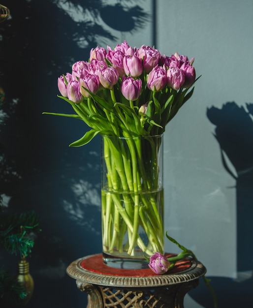 Un ramo de tulipanes rosados con hojas verdes dentro de un jarrón