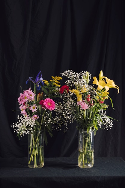 Ramos de flores brillantes en jarrones con agua.