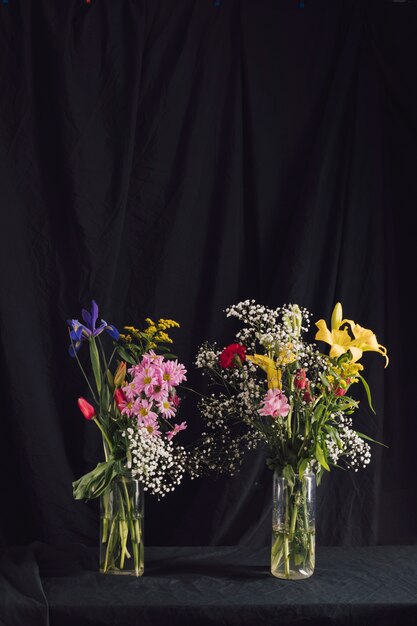 Ramos de maravillosas flores brillantes en jarrones con agua.