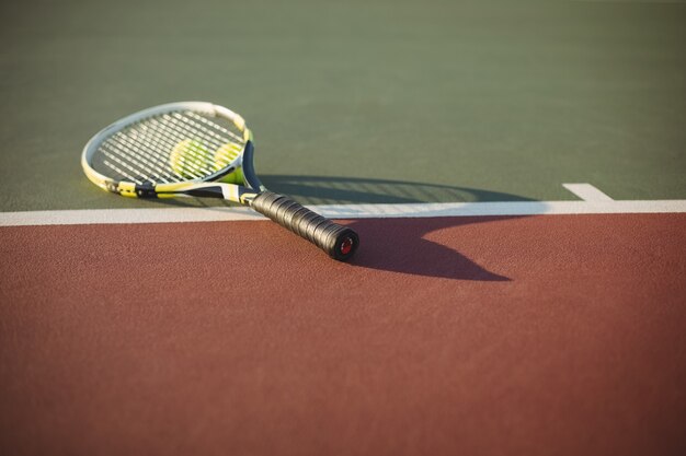 Raqueta de tenis y pelotas en la cancha