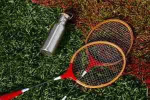 Foto gratuita raquetas de bádminton y matraz sobre hierba