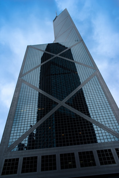 Foto gratuita un rascacielos alto en una fachada de vidrio con el reflejo de otro rascacielos en hong kong