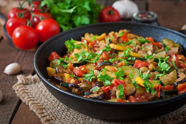 Ratatouille de verduras en sartén sobre una mesa de madera