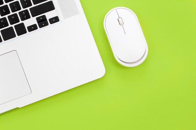 Ratón de computadora y computadora portátil sobre un fondo verde aislado plano