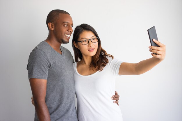 Raza mixta pareja de estudiantes tomando selfie común con el teléfono.