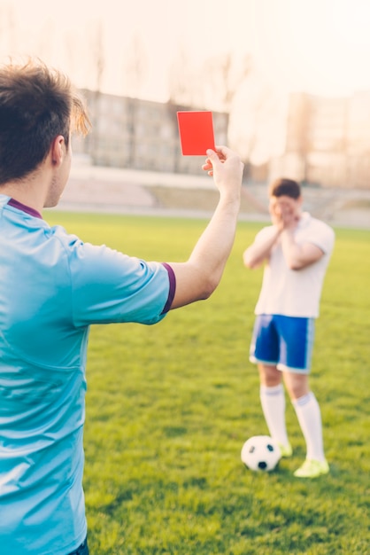 Árbitro sin rostro que muestra la tarjeta roja al atleta