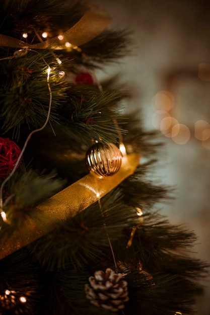 Árbol de navidad decorado con cinta dorada y guirnalda.