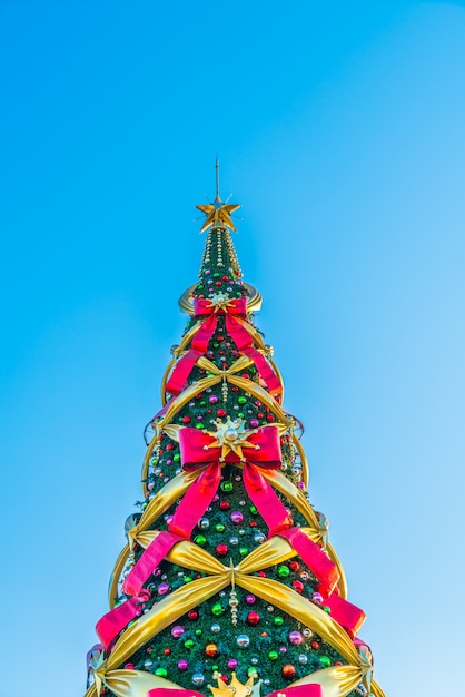 Árbol de navidad con lazos grandes en un fondo azul en vertical