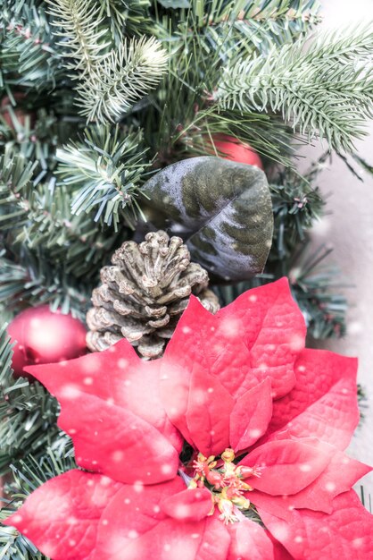 Árbol de navidad con piñas y una flor roja