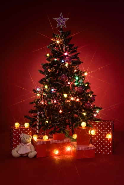 Árbol de navidad con regalos en fondo rojo