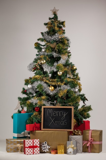 Árbol de navidad con regalos y una pizarra negra