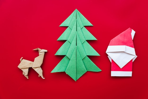 Árbol de Navidad; reno; Papá Noel origami de papel sobre fondo rojo