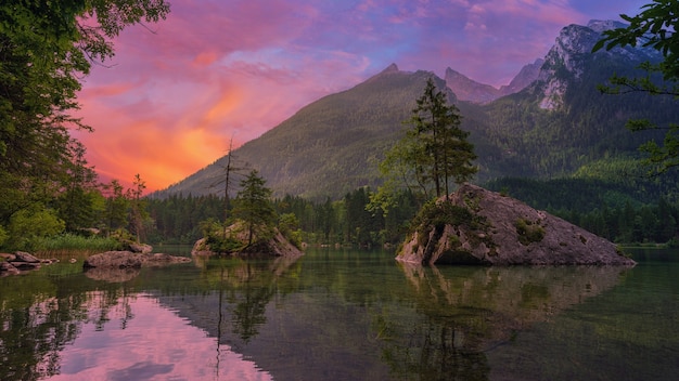 Árboles verdes cerca del lago y la montaña durante la puesta de sol