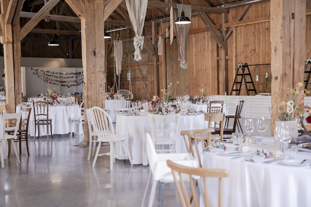 Área de bodas de madera bellamente decorada con mesas cubiertas de blanco