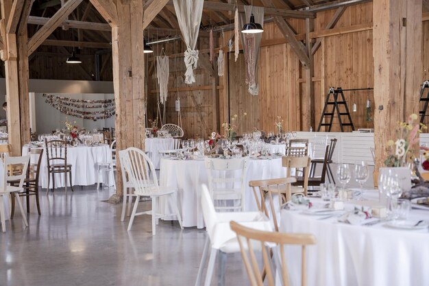 Área de bodas de madera bellamente decorada con mesas cubiertas de blanco