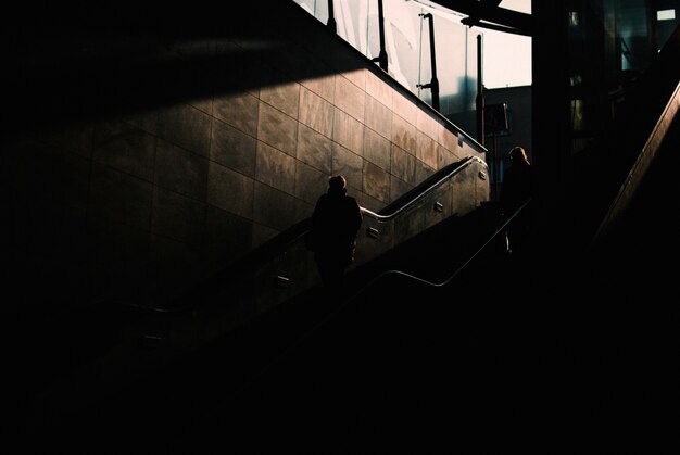 Área oscura subterránea con dos personas bajando las escaleras