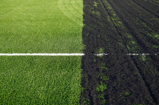 Realización de un campo de fútbol de césped artificial con superficie de césped sintético verde y gránulos de caucho