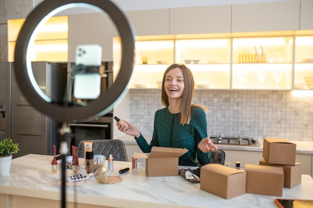 Rebaja. Mujer joven en vestido verde realizando venta cosmética en línea