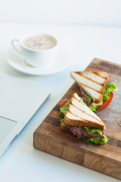 Rebanada de bocadillos de jamón y taza de café en el fondo