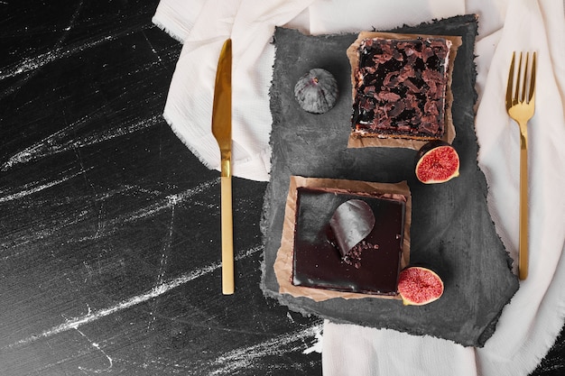 Una rebanada cuadrada de tarta de queso con chocolate sobre una tabla de piedra.