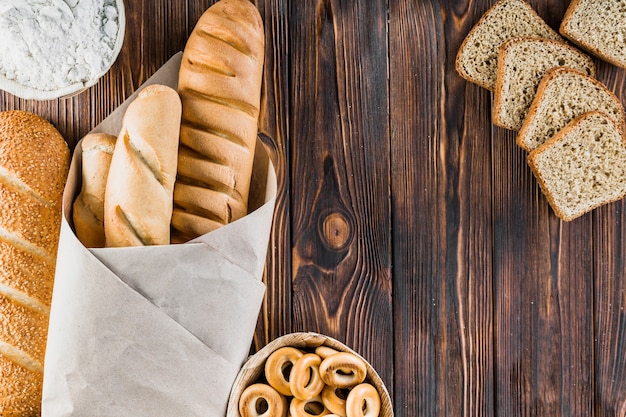 Rebanada de pan, baguettes, bagels, harina en el fondo de madera