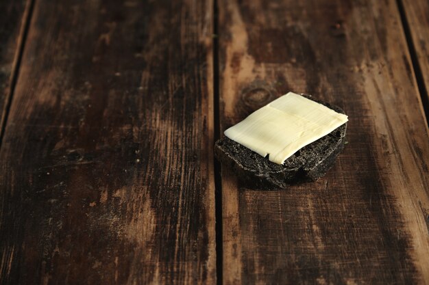 Rebanada de pan casero de lujo de carbón negro con mantequilla aislado sobre mesa de madera rústica