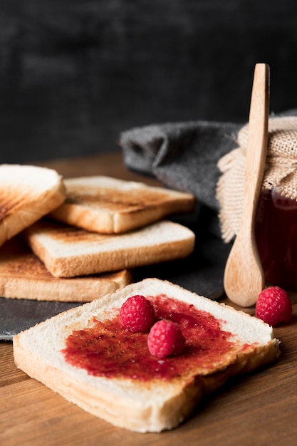 Foto gratuita rebanada de pan con mermelada de frambuesa y cuchara