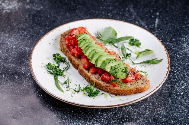 Una rebanada de pan negro con cubitos de tomate y rodajas de pepino.