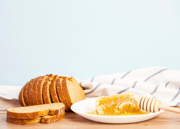 Rebanada de pan y panal para el desayuno en superficie de madera