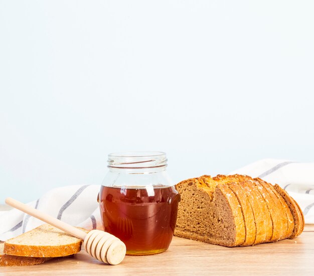 Rebanada de pan y tarro de miel para el desayuno sobre el escritorio de madera