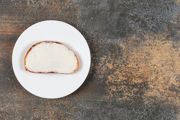 Rebanada de pan tostado con crema agria en un plato blanco.