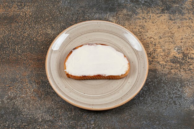 Rebanada de pan tostado con crema agria en un plato de cerámica.