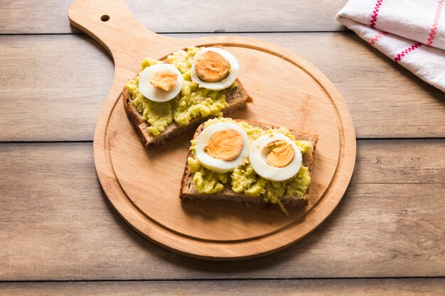 Rebanada de pan tostado con huevo cocido en tabla de cortar