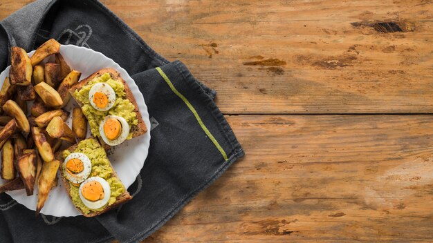 Rebanada de pan tostado con huevo cocido y trozos de pan tostado en un plato