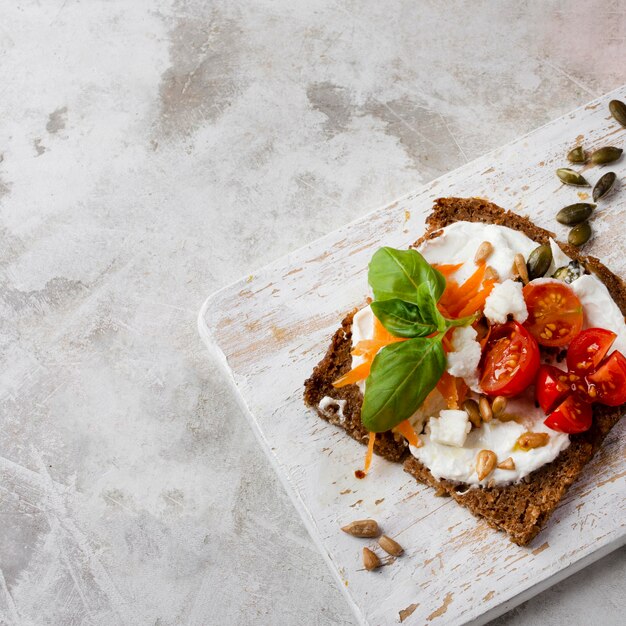 Rebanada de pan tostado con tomates cherry en mármol vista alta