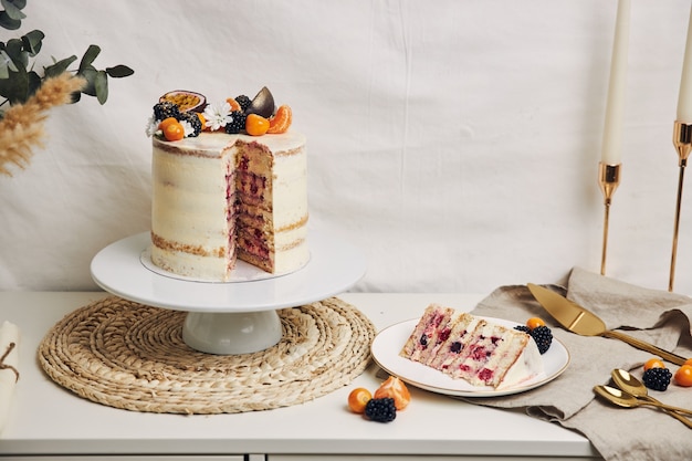 Rebanada de pastel con bayas y maracuyá en la mesa detrás de un fondo blanco.