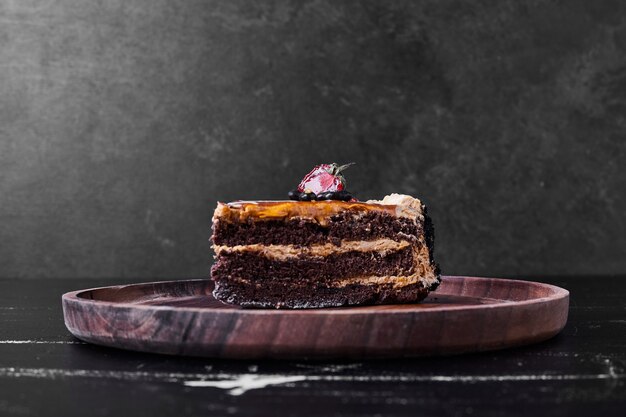 Una rebanada de pastel de caramelo de chocolate en una placa de madera.