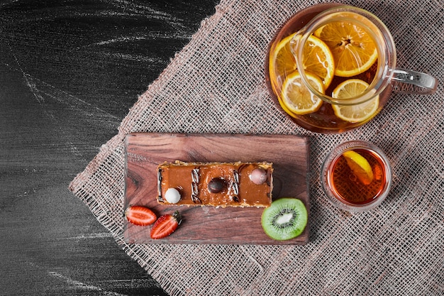 Rebanada de pastel de caramelo con limonada en un plato de madera.