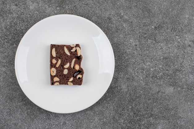 Rebanada de pastel casero fresco en un plato blanco. Maní y chocolate.