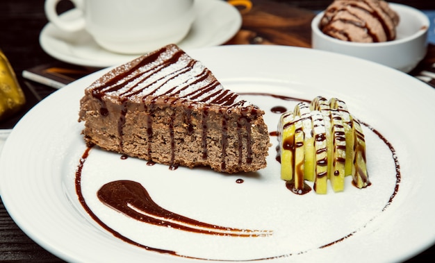 Rebanada de pastel de chocolate y chocolate con rodajas de manzana y salsa de chocolate.