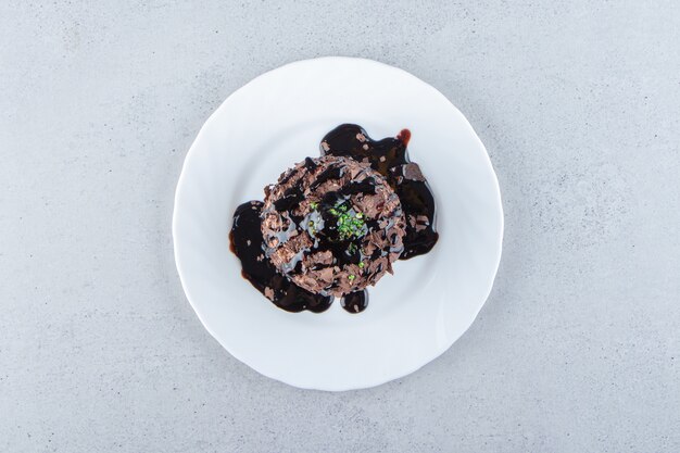 Rebanada de pastel de chocolate decorado con syrop en plato blanco. Foto de alta calidad