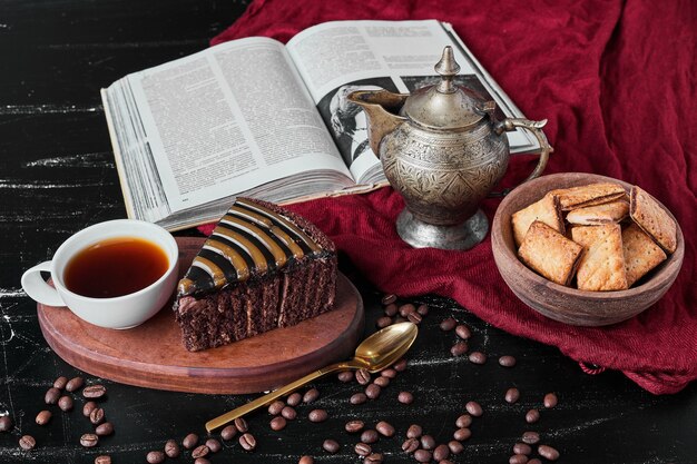 Rebanada de pastel de chocolate con galletas saladas y una taza de té.