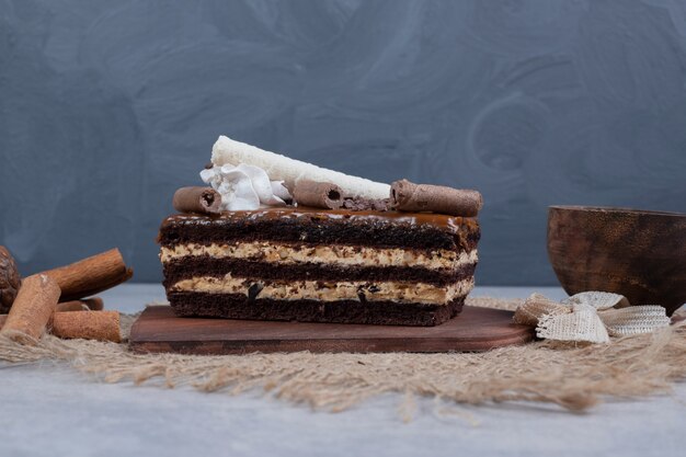 Rebanada de pastel de chocolate con hojas sobre mesa de mármol. Foto de alta calidad