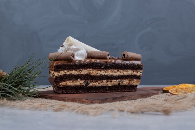 Rebanada de pastel de chocolate con hojas sobre mesa de mármol. Foto de alta calidad