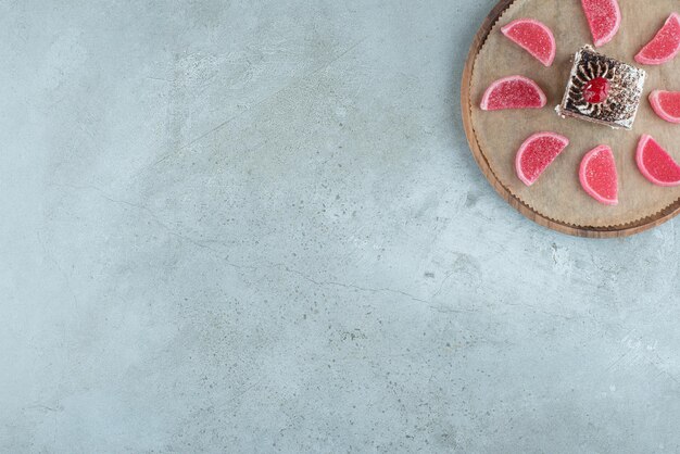 Rebanada de pastel de chocolate con mermeladas en placa de madera. Foto de alta calidad