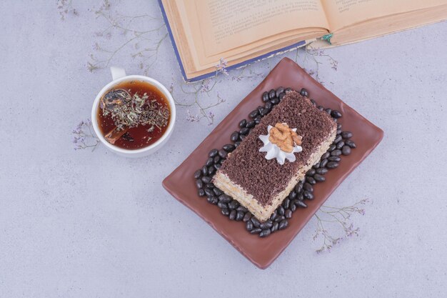 Una rebanada de pastel con chocolate picado y una taza de té de hierbas