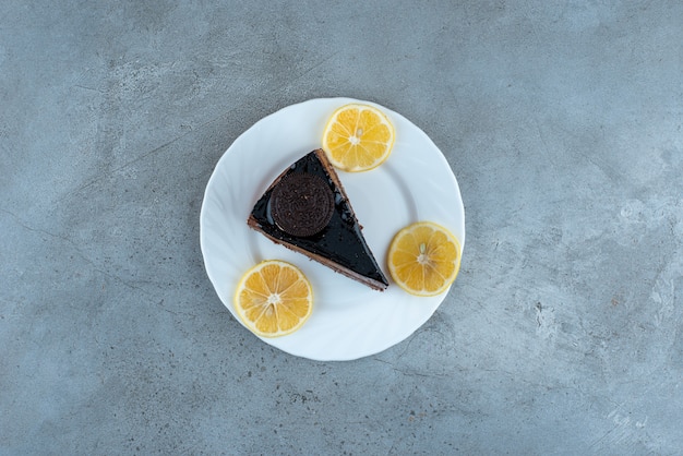 Foto gratuita rebanada de pastel de chocolate con rodajas de limón en un plato blanco. foto de alta calidad