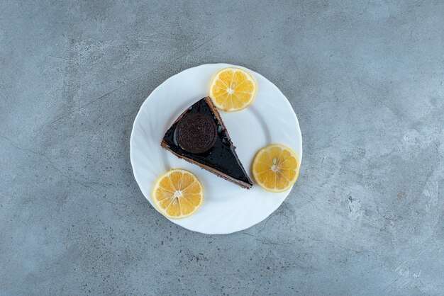 Rebanada de pastel de chocolate con rodajas de limón en un plato blanco. Foto de alta calidad