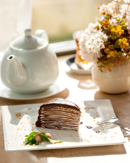 Rebanada de pastel de crepe de chocolate con crema blanca