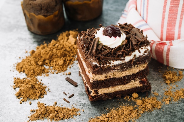 Rebanada de pastel decorativo con chocolate en polvo en el mostrador de la cocina